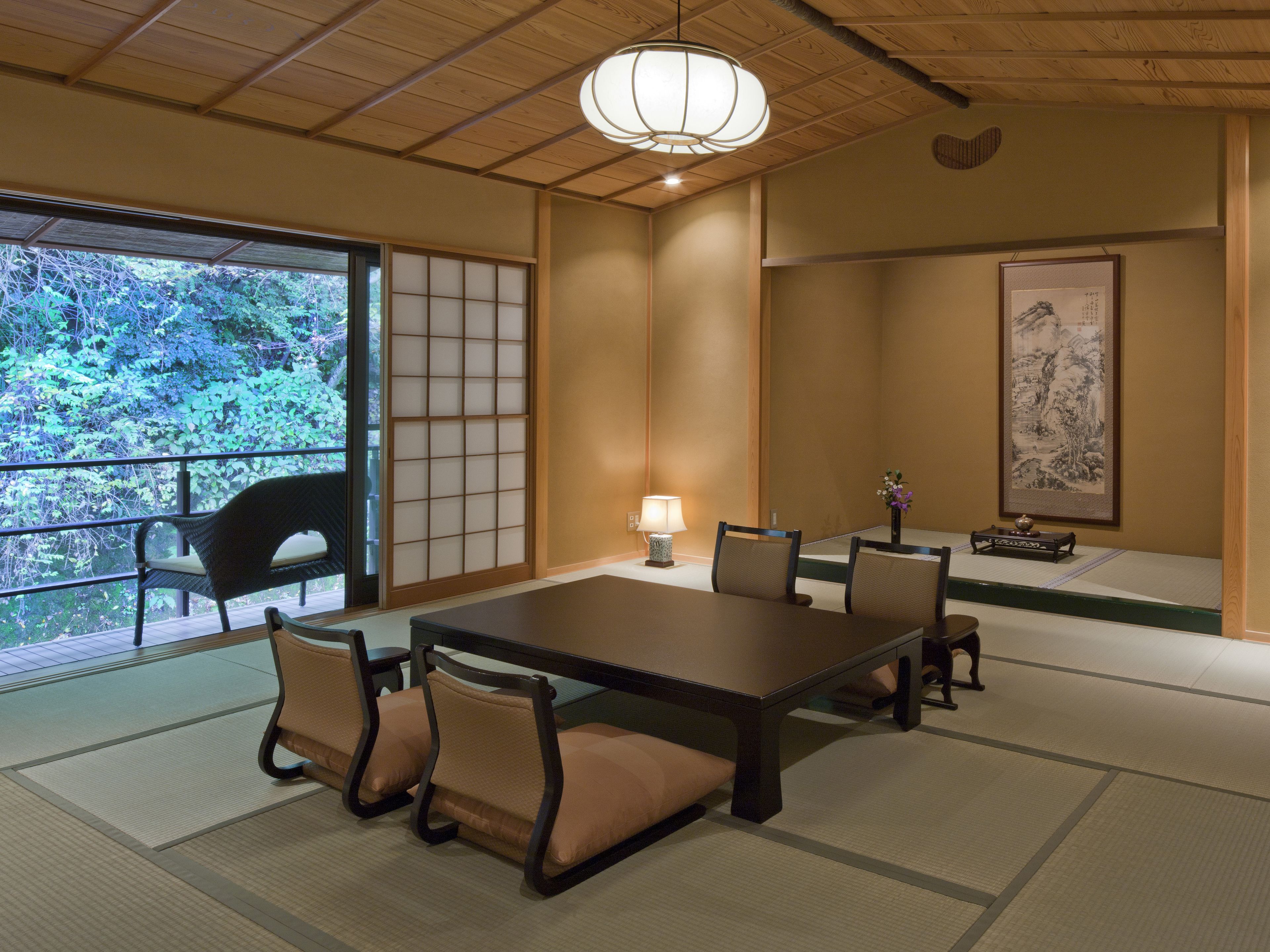A traditional Japanese room with tatami flooring, a low table, and chairs.