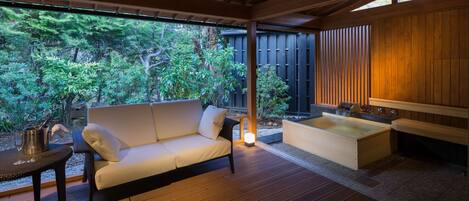 Una terraza de madera con un sofá y un jacuzzi.