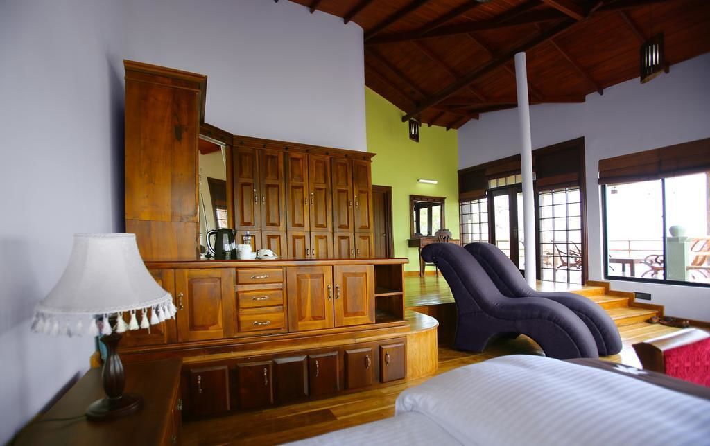 Ein Schlafzimmer mit Holzschrank, Schreibtisch mit Lampe, Liegestuhl und Bett.