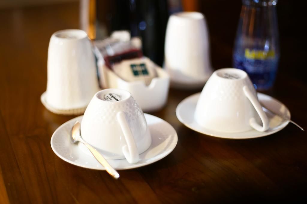 Una mesa con teteras y tazas blancas, una botella y una caja de bolsitas de té.