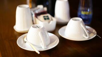 Una mesa con teteras y tazas blancas, una botella y una caja de bolsitas de té.