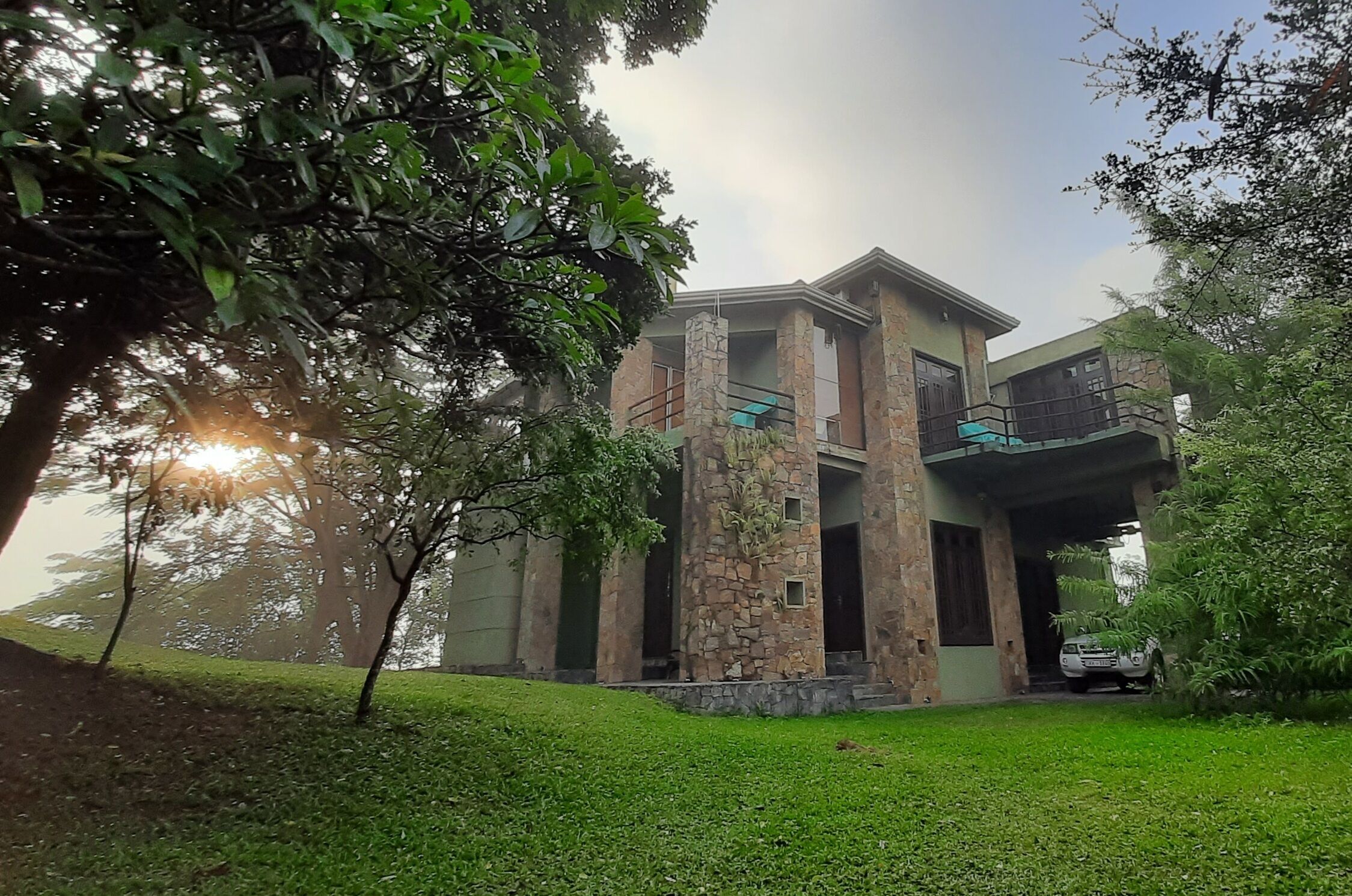 A modern two-story house with a stone facade, a covered porch, and a car parked in the driveway.