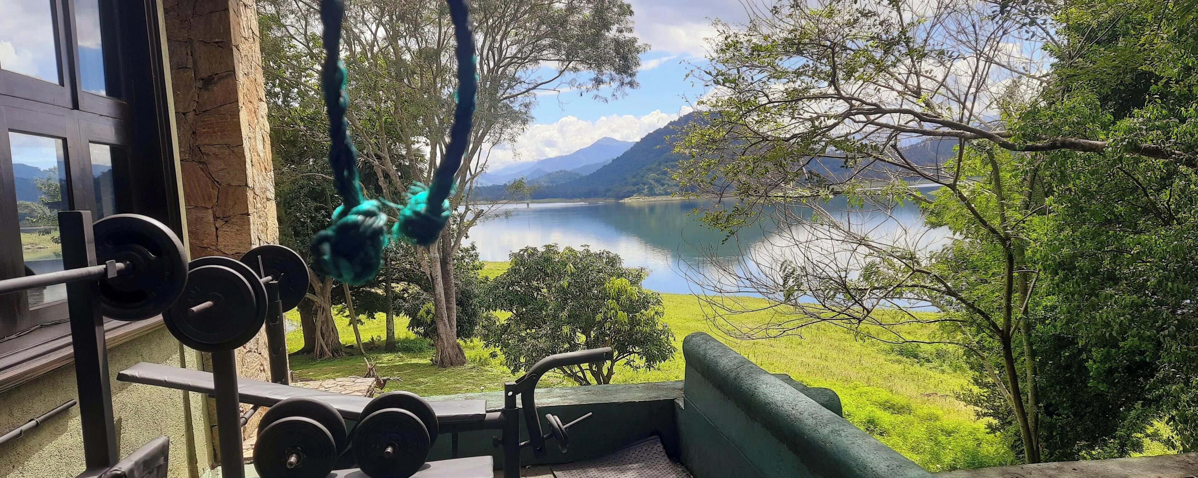 A gym with outdoor exercise equipment overlooking a lake and mountains.