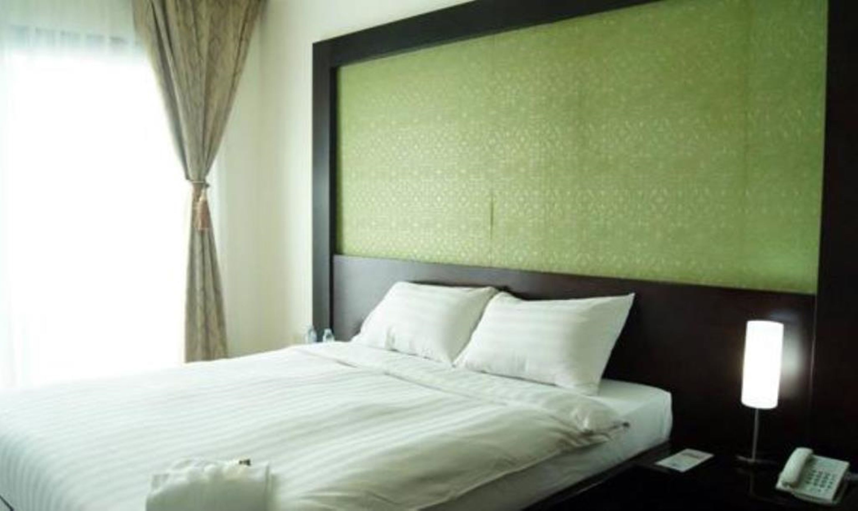 Una habitación de hotel con cama, mesita de noche y teléfono.