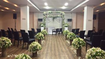 A conference room with rows of chairs, a stage with floral decorations, and a podium.