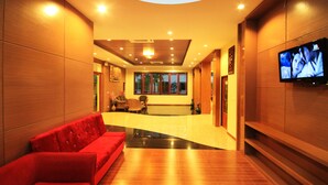 A modern lobby with a reception desk, a red sofa, and a television on the wall. - Chaophaya Thara Riverside (Chai Nat)