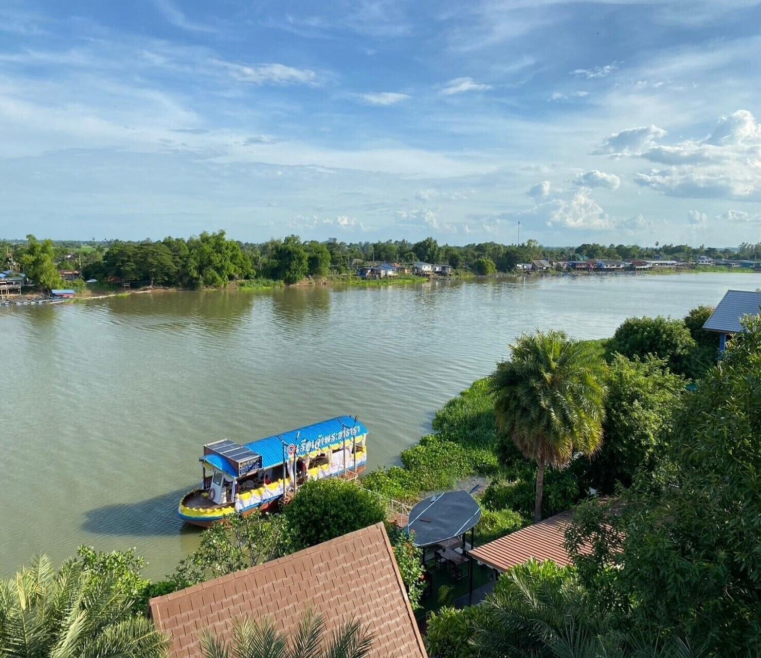 Ein Fluss mit einem Boot, das an einem Haus mit Ziegeldach anlegt.