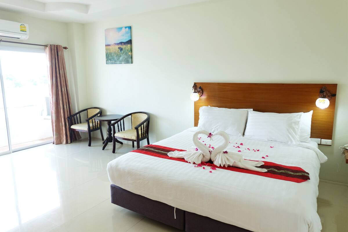 Habitación de hotel con una cama grande, un cabecero de madera, una mesita con sillas y un cuadro en la pared.