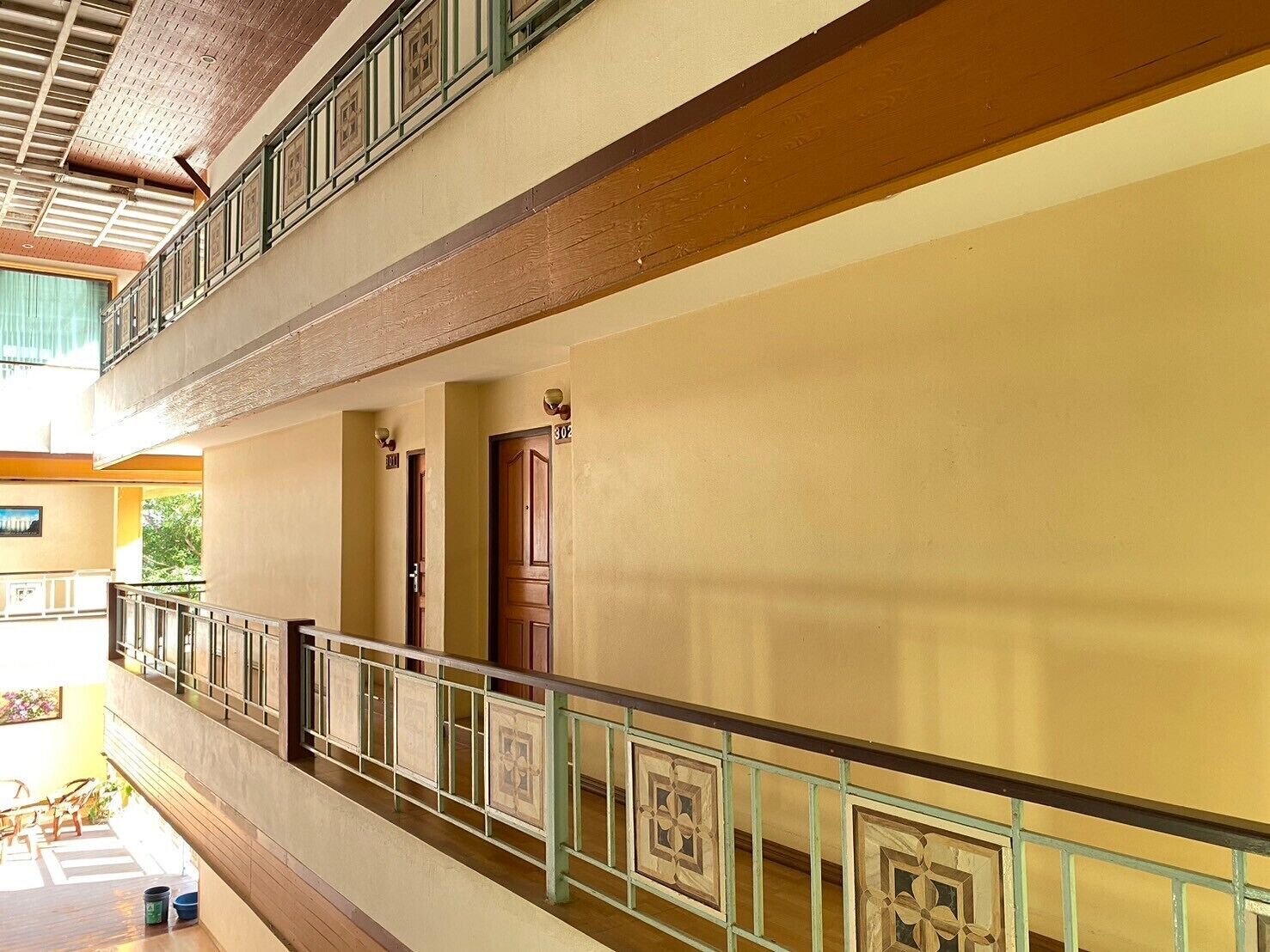 Un edificio de varios niveles con balcón, puertas de madera y piso de baldosas.