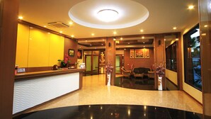 A hotel reception area with a reception desk, a waiting area with seating, and a large window offering a view of the outside. - Chaophaya Thara Riverside (Chai Nat)