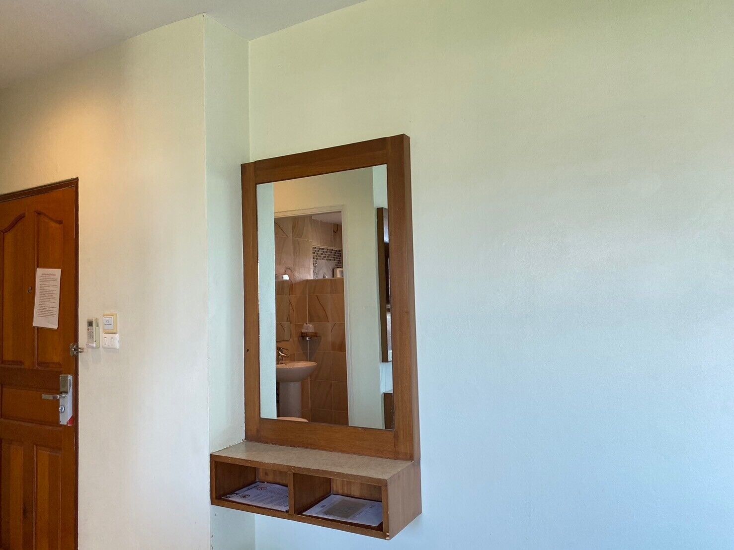 Un baño con espejo de marco de madera, inodoro y lavamanos.