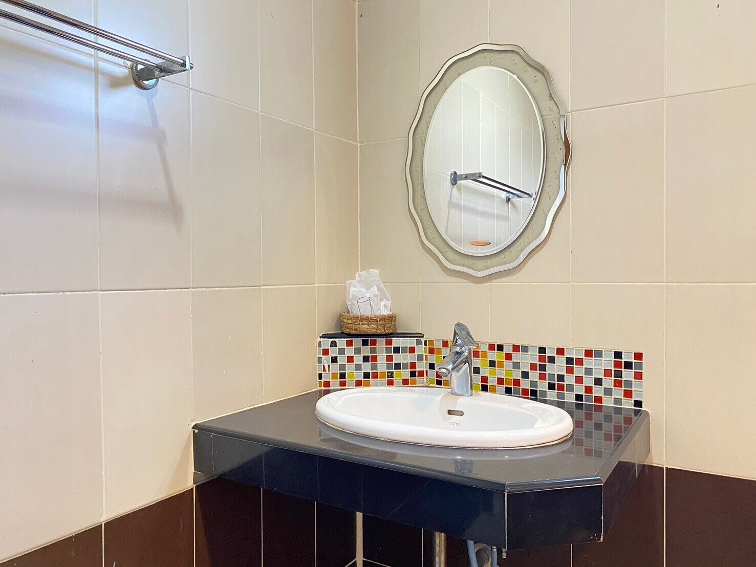 Et badeværelse med en hvid vask, et spejl med dekorativ ramme og et flisebeklædt backsplash.