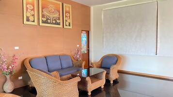 A modern lobby with a sofa and two armchairs, a glass coffee table, and decorative wall art.