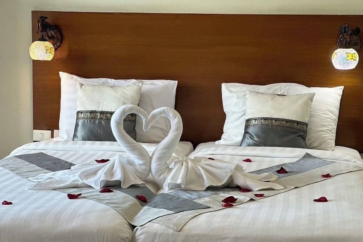 Habitación de hotel con una cama grande, dos almohadas, cabecero de madera y una lámpara de pared decorativa.