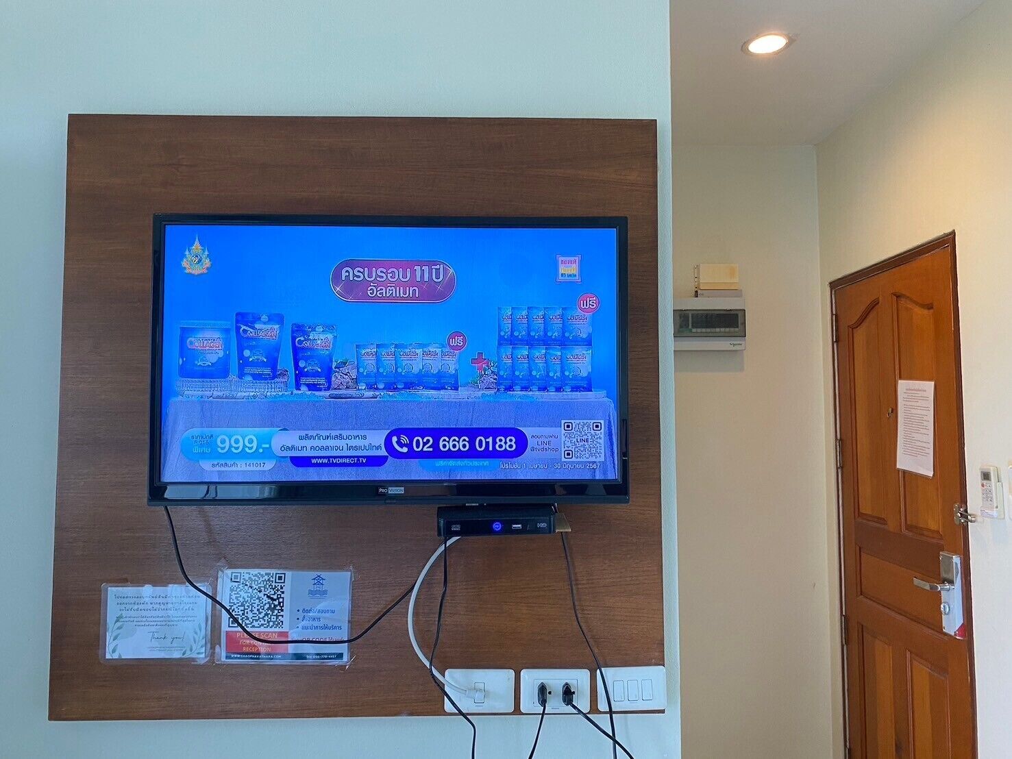 A television mounted on a wooden panel with a digital display advertising a product.