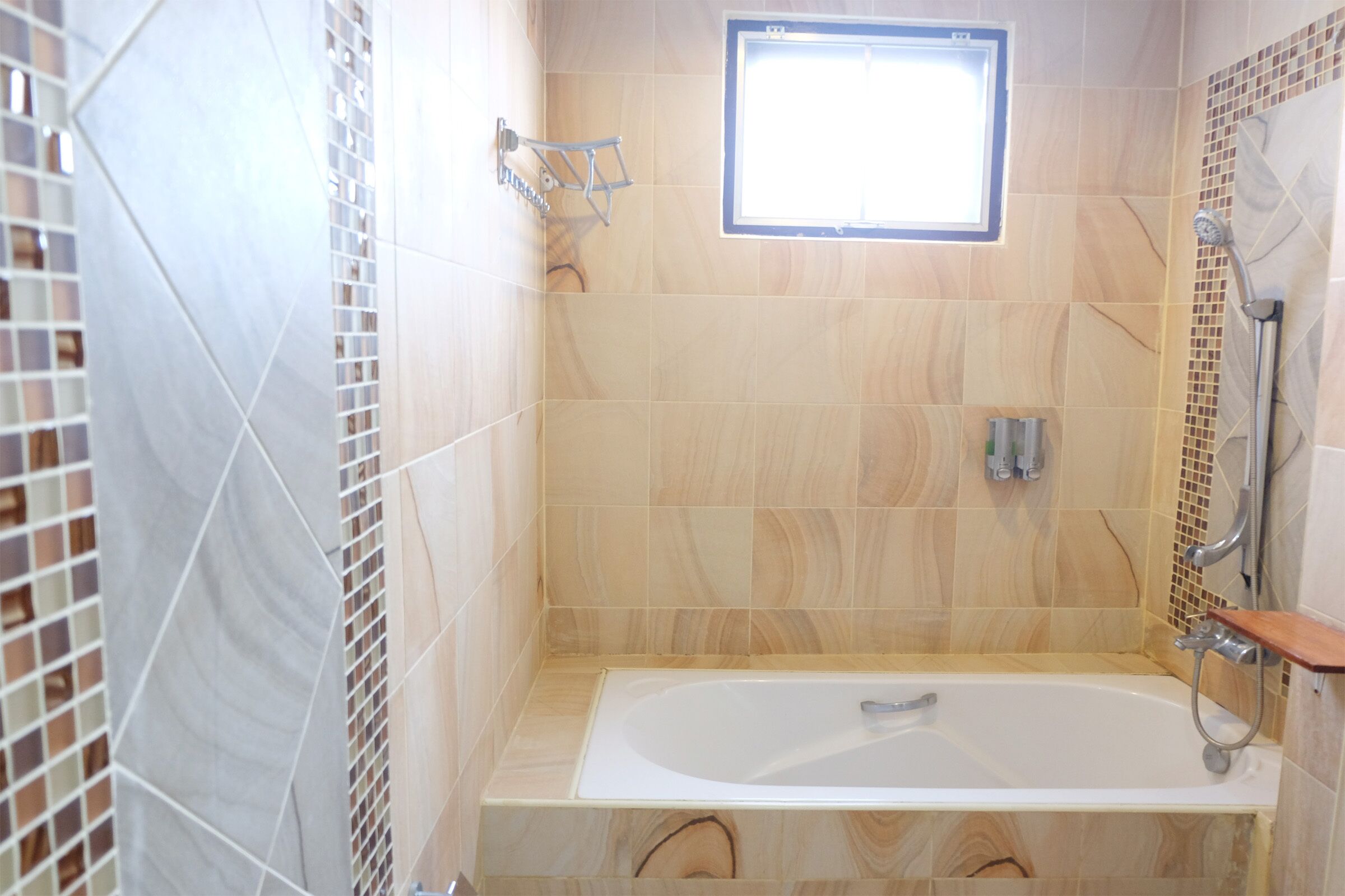 A bathroom with a bathtub, a shower, and a window.