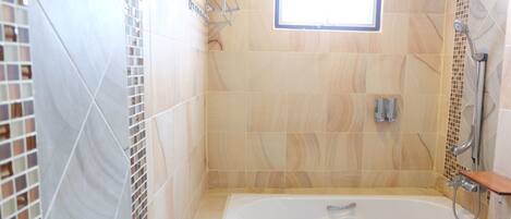 A bathroom with a bathtub, a shower, and a window.