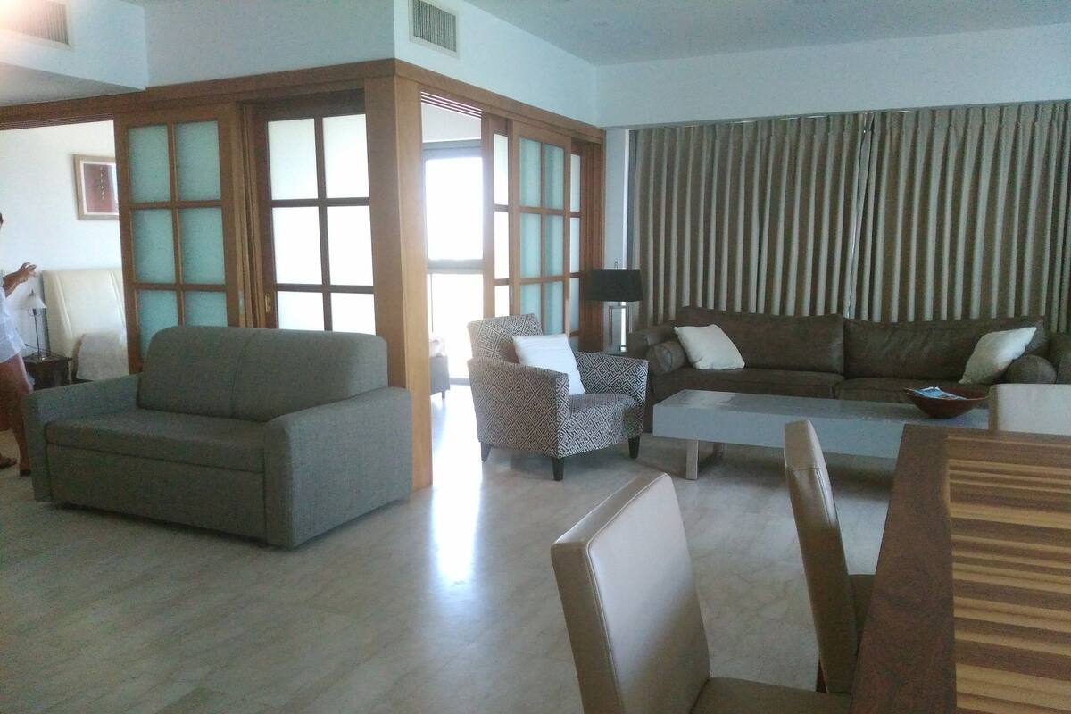 Ein Wohnzimmer mit grauem Sofa, einem gemusterten Sessel und einem Holztisch.