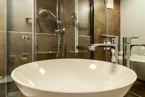 Een moderne badkamer met een groot, vrijstaand wastafelmeubel, een douche met glazen wand en een apart wastafeltje met spiegel.