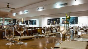 L’intérieur d’un restaurant, avec des tables dressées pour le service, des menus accrochés aux murs et un bar à l’arrière-plan.
