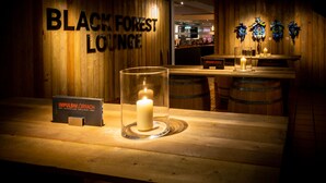 A wooden bar area with a sign for 'Black Forest Lounge' and a candle on the counter. - IMPULSIV Hotel & Sportresort (Loerrach)
