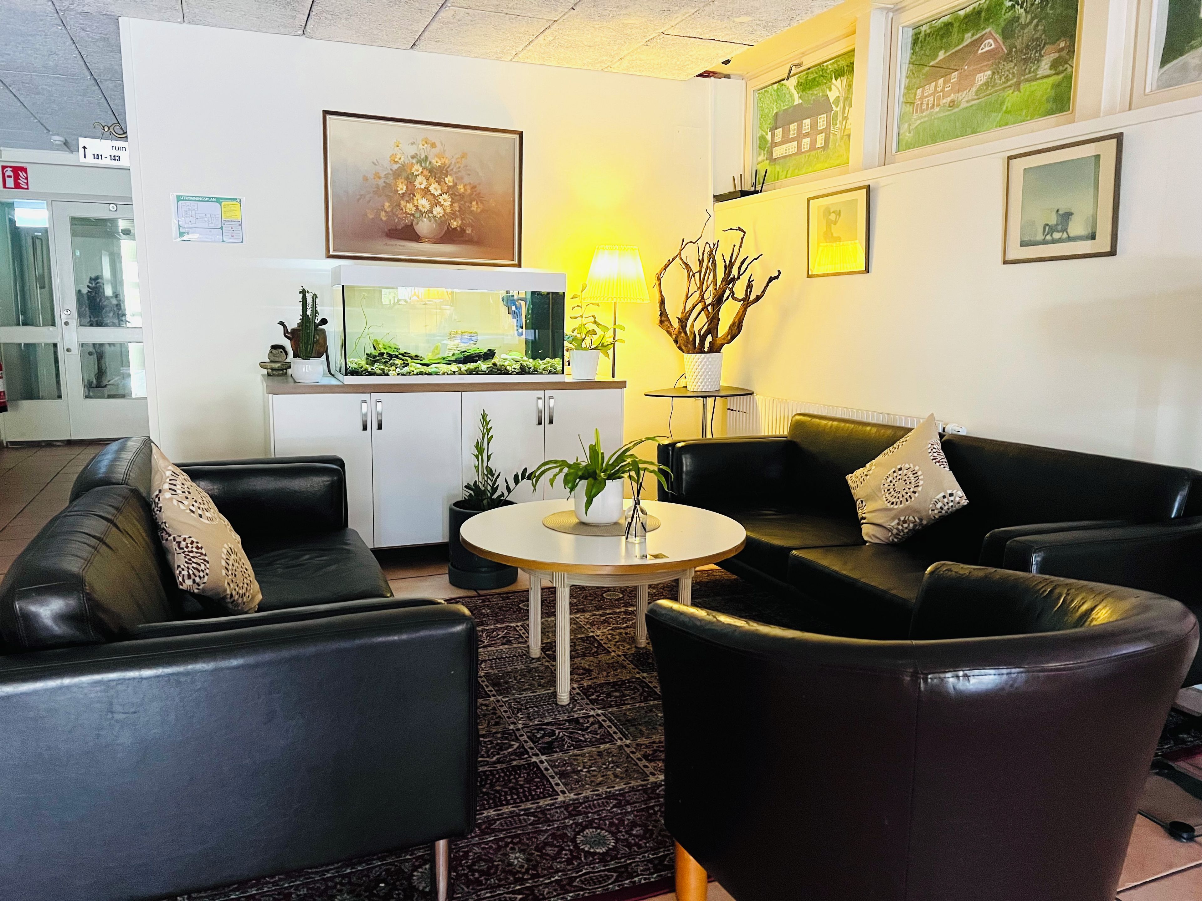 A modern living room with black leather sofas, a round coffee table, and a small potted plant.