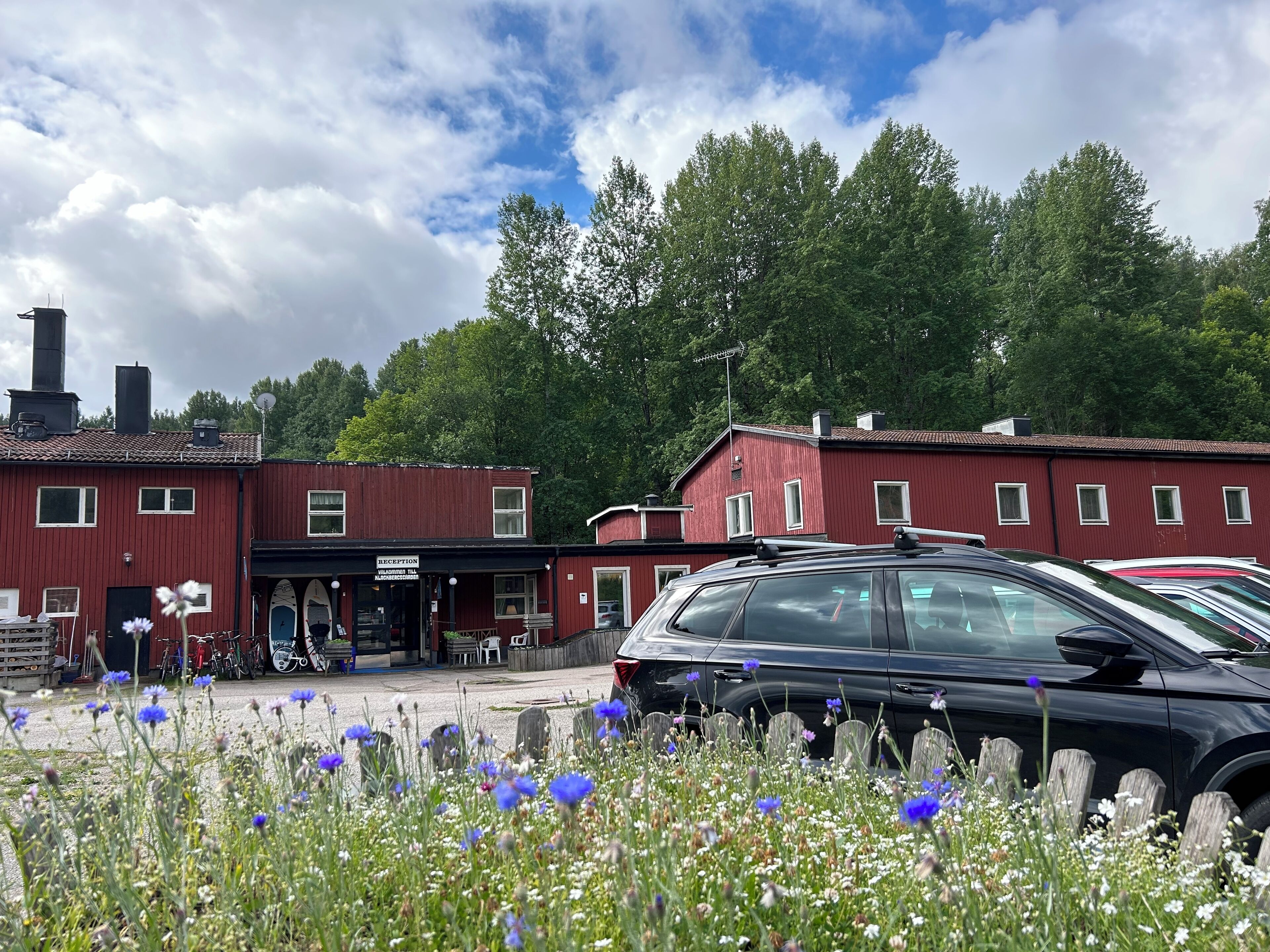 A red building with a reception area and a parking lot with cars.