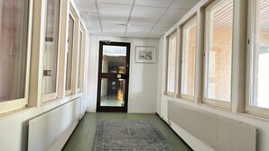 En gang med store vinduer, en radiator og et tæppe.