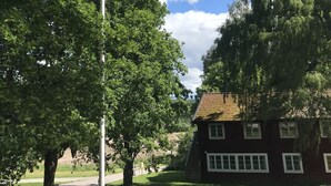 Flagstang med flag, en bygning og træer i en græsplæne.