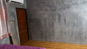 A room with two beds, a wooden floor, a grey textured wall, and a wooden door. - Baan Raiplaysoi Homestay (Photharam)