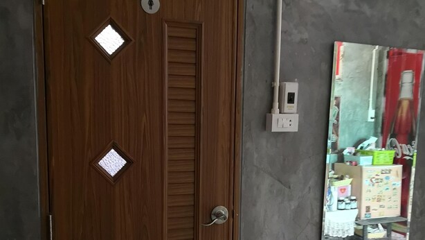 A wooden door with diamond-shaped windows and a mirror reflecting a room with patterned flooring. - Baan Raiplaysoi Homestay (Photharam)