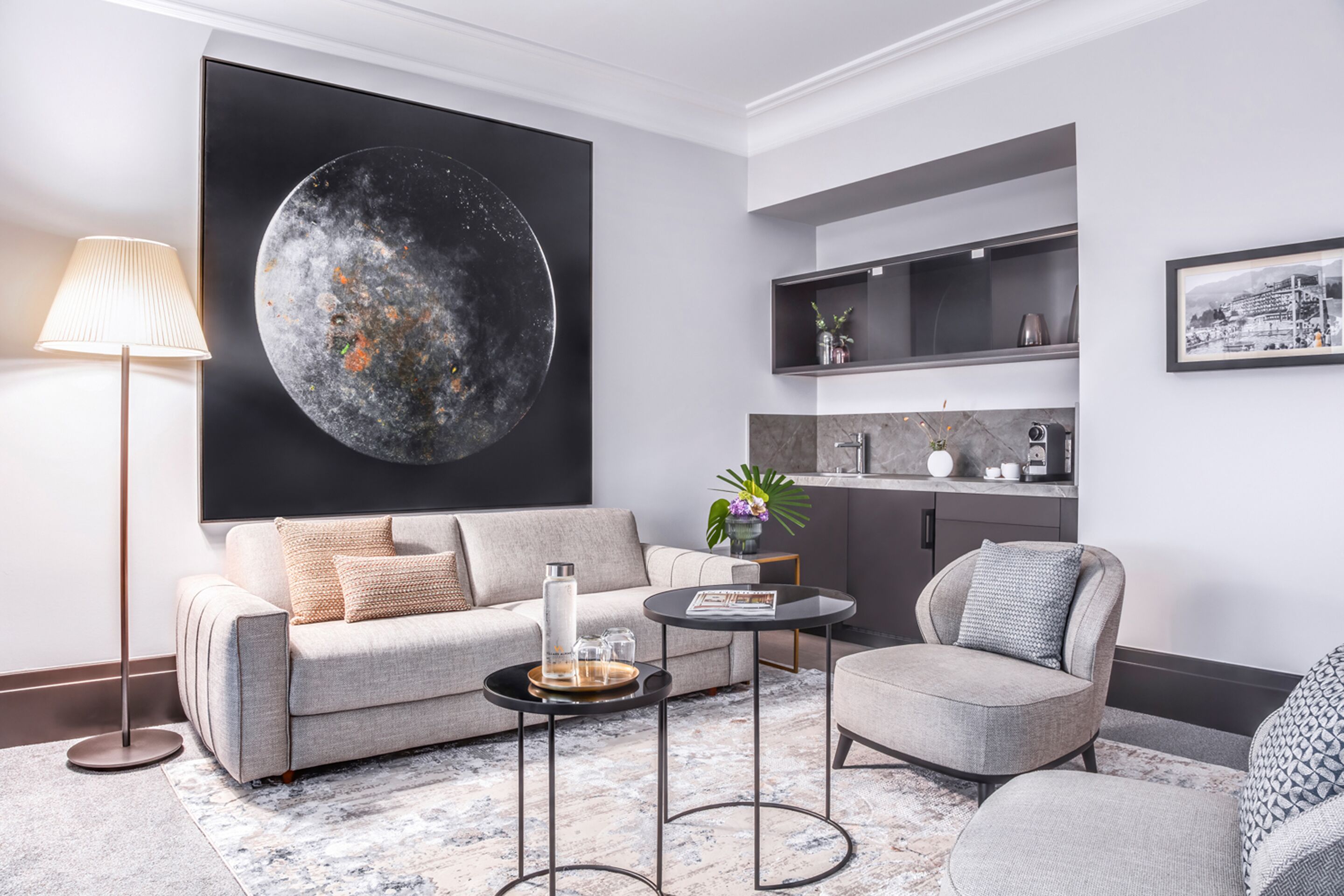 Una sala de estar moderna con un cuadro abstracto grande, un sofá, una mesa de centro y una silla.
