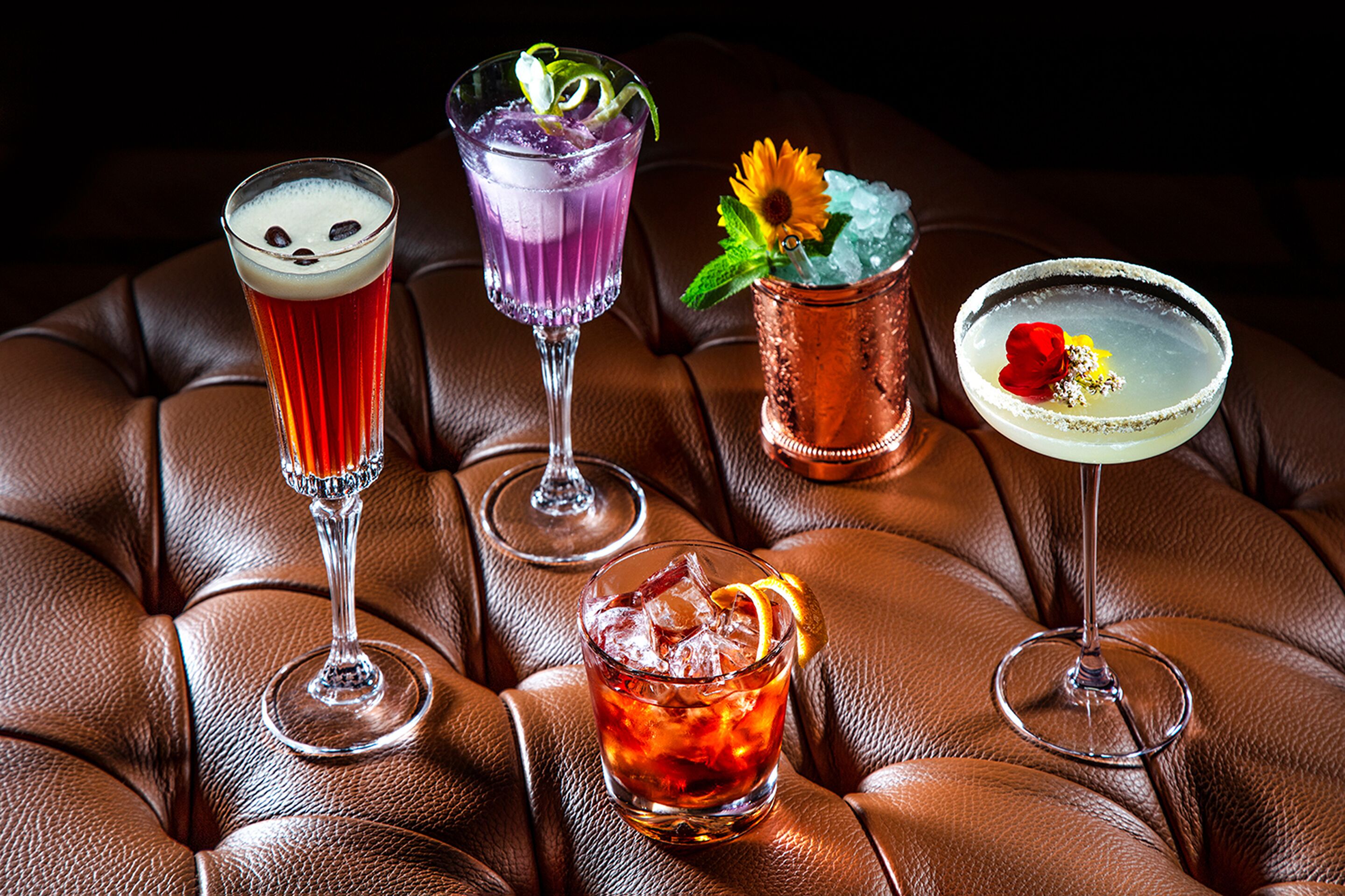 Four cocktails on a leather couch.