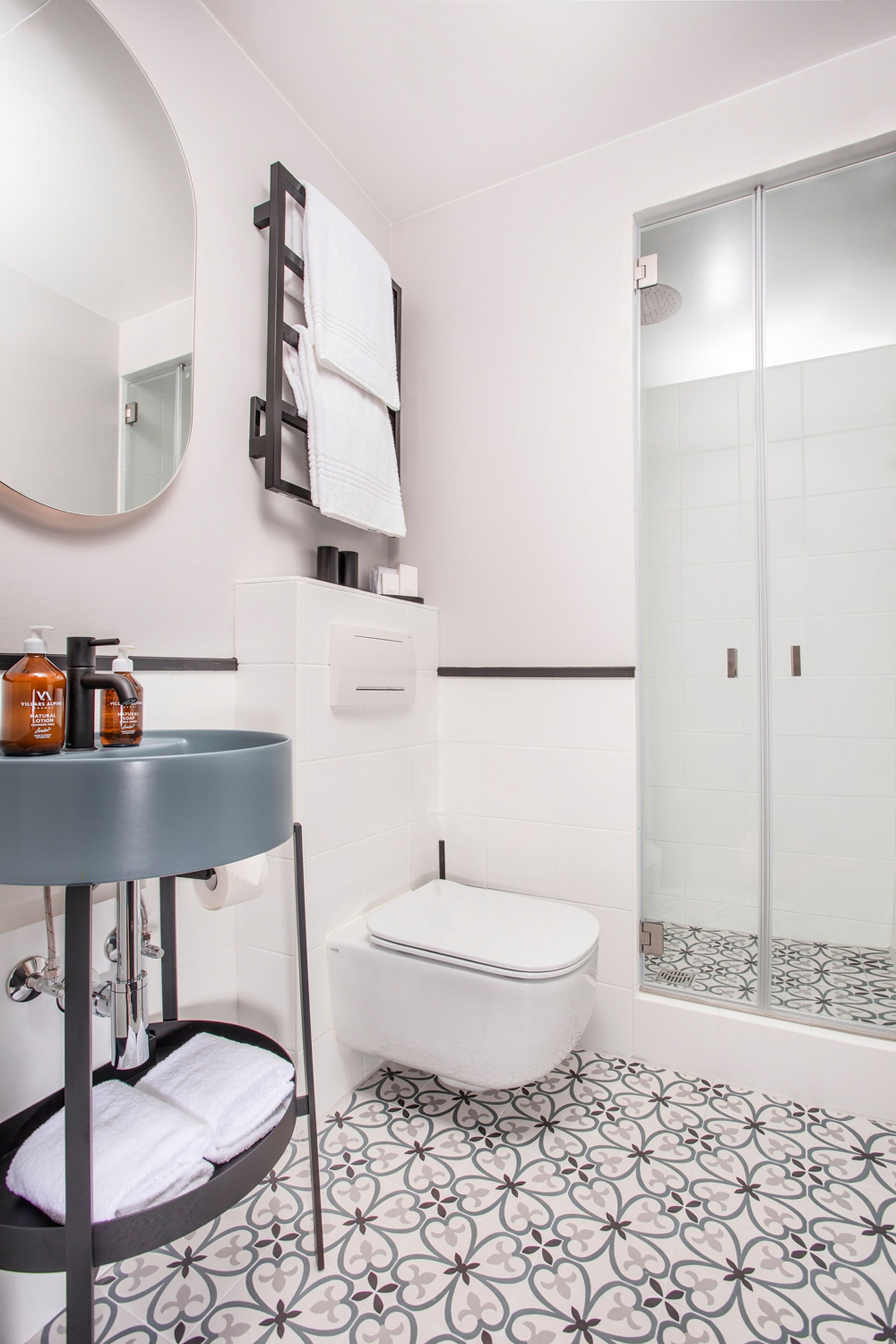 Een moderne badkamer met een rond wastafeltje, toilet in het wit en een douchecabine van glas.