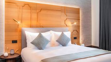 Een moderne hotelkamer met een groot bed, een houten hoofdeinde en nachtkastjes.