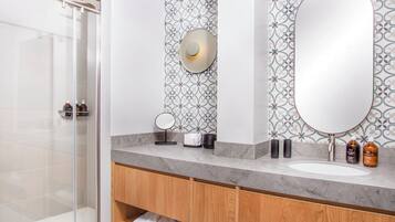 A modern bathroom with a glass shower enclosure, a marble sink, and patterned wall tiles.