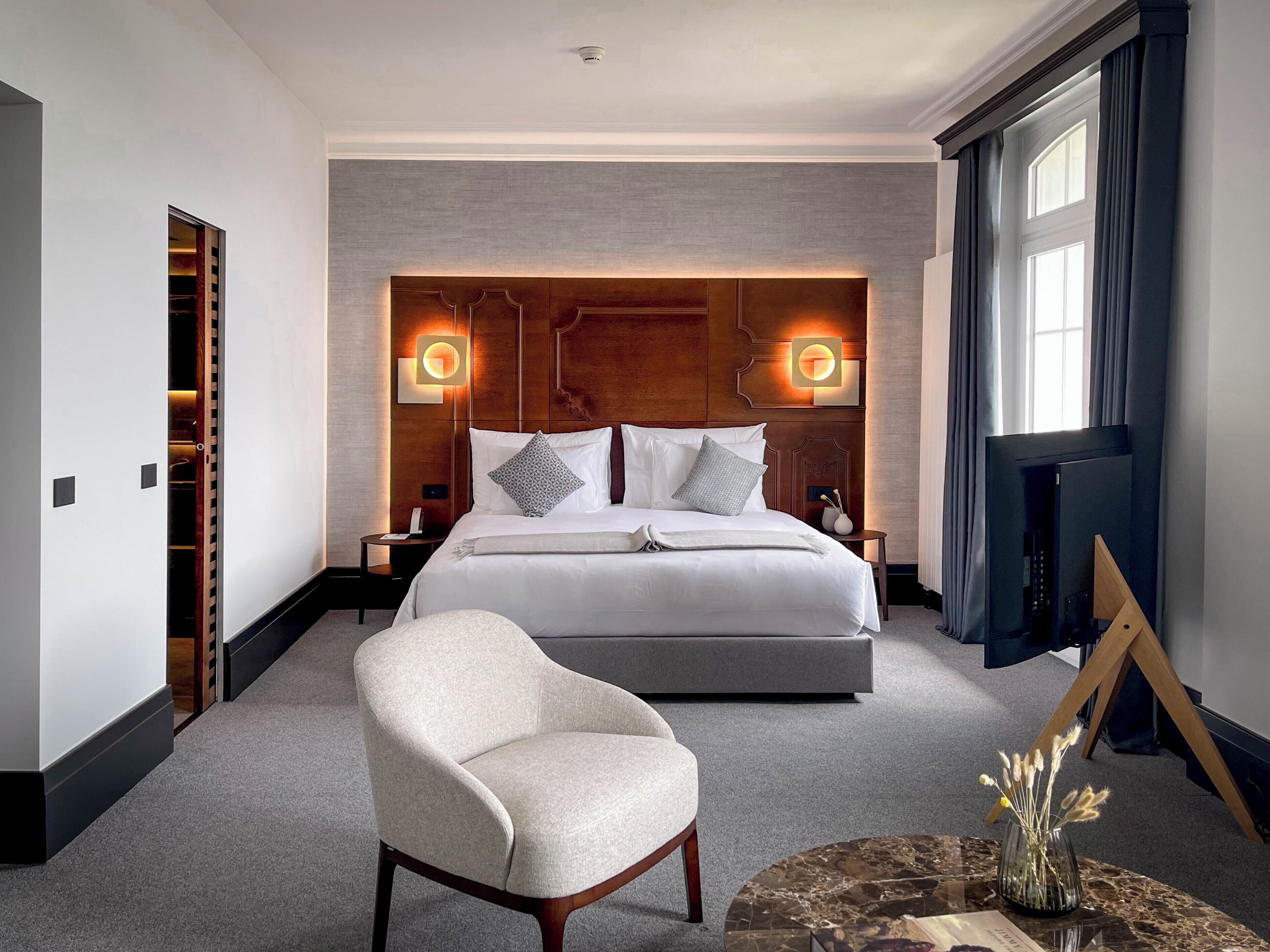 Una habitación de hotel moderna con una cama grande, una zona de estar y un televisor.