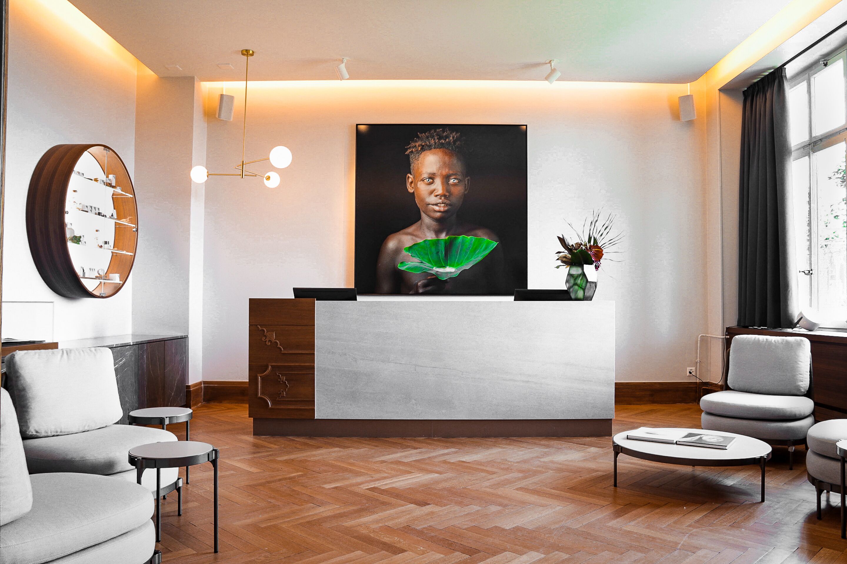 A modern reception area with a marble counter, a large framed portrait, and a wooden herringbone floor.