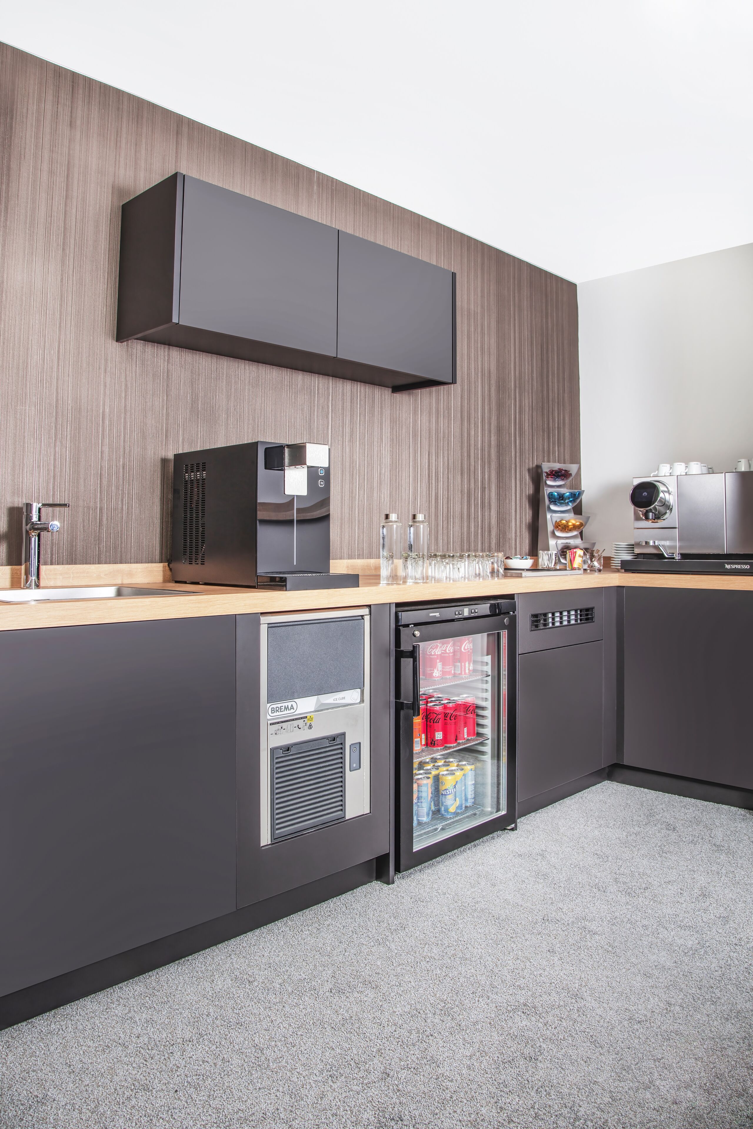 A modern kitchen with a built-in coffee machine, a mini-fridge, and a dishwasher.