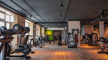 A gym with cardio machines, weightlifting equipment, and a wooden floor.