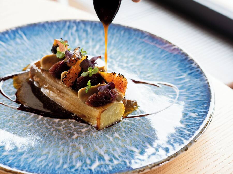 A dessert on a blue plate with a sauce being poured over it.