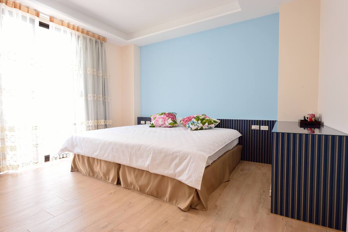 A bedroom with a bed, curtains, a dresser, and a window.