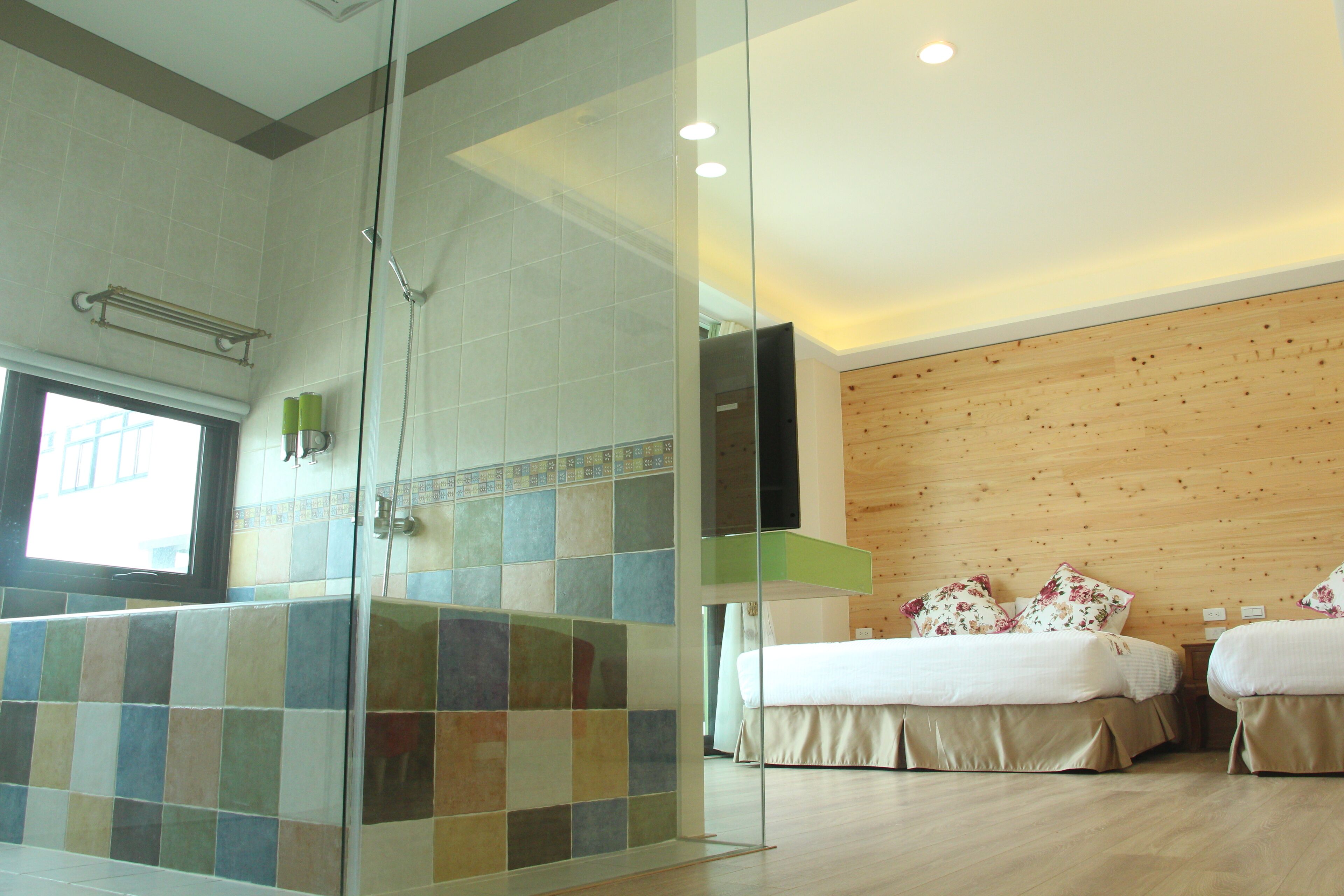 A hotel room with a shower area, a bed, and a wooden wall.