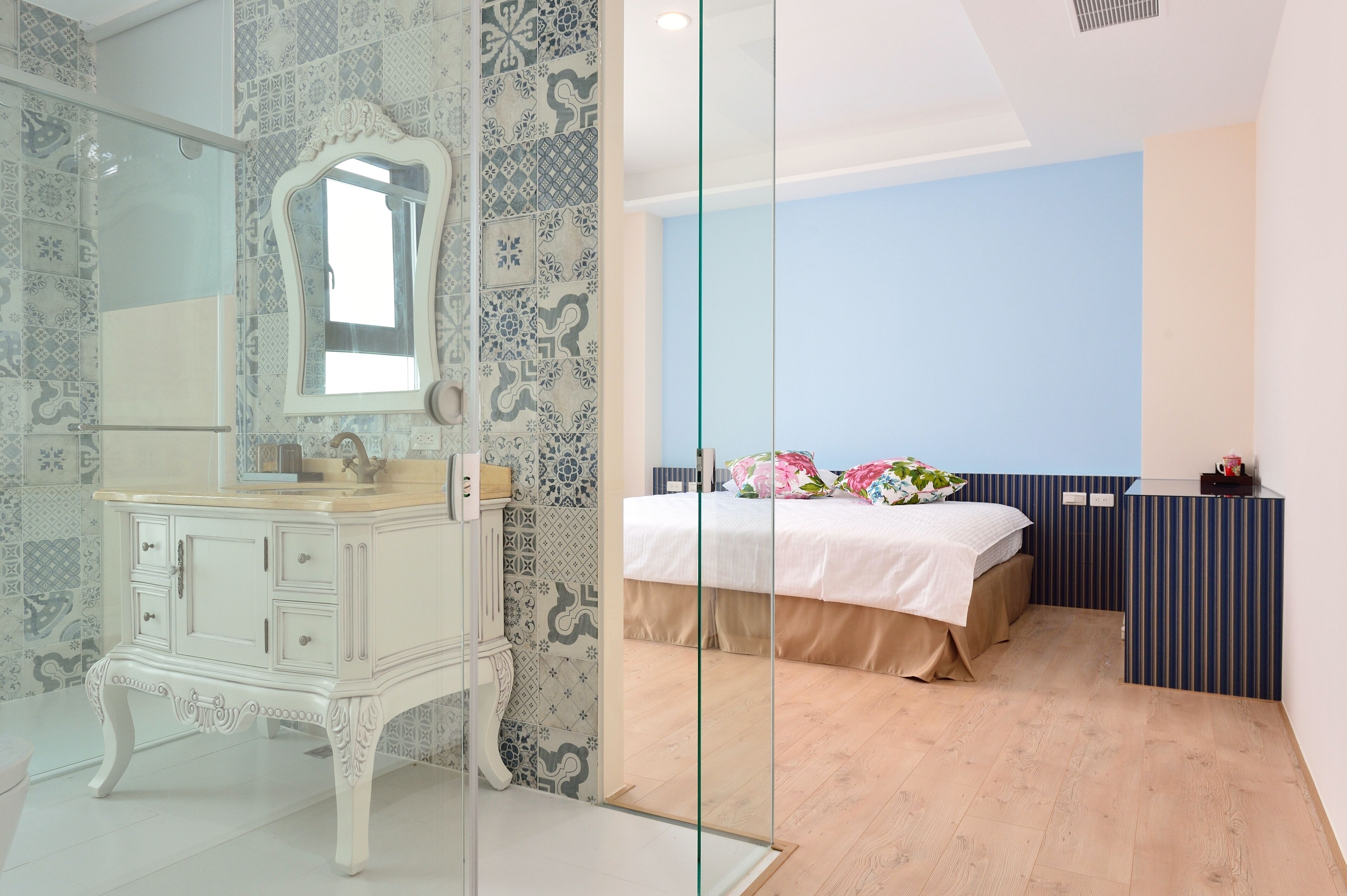 A modern bathroom with a white vanity, a large mirror, and patterned tiles.