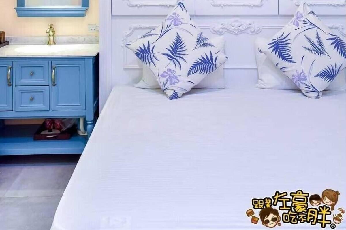 A bedroom with a large bed, a blue dresser, a mirror, and white walls with decorative moldings.