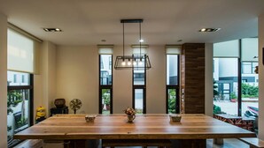 Un vaste espace dédié à la salle à manger, avec une grande table en bois, des bancs et un luminaire suspendu.