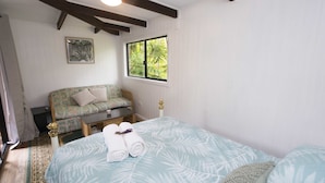 A bedroom with a bed, a sofa, a window, and a painting on the wall. - Nimbin Waterfall Retreat (Nimbin)