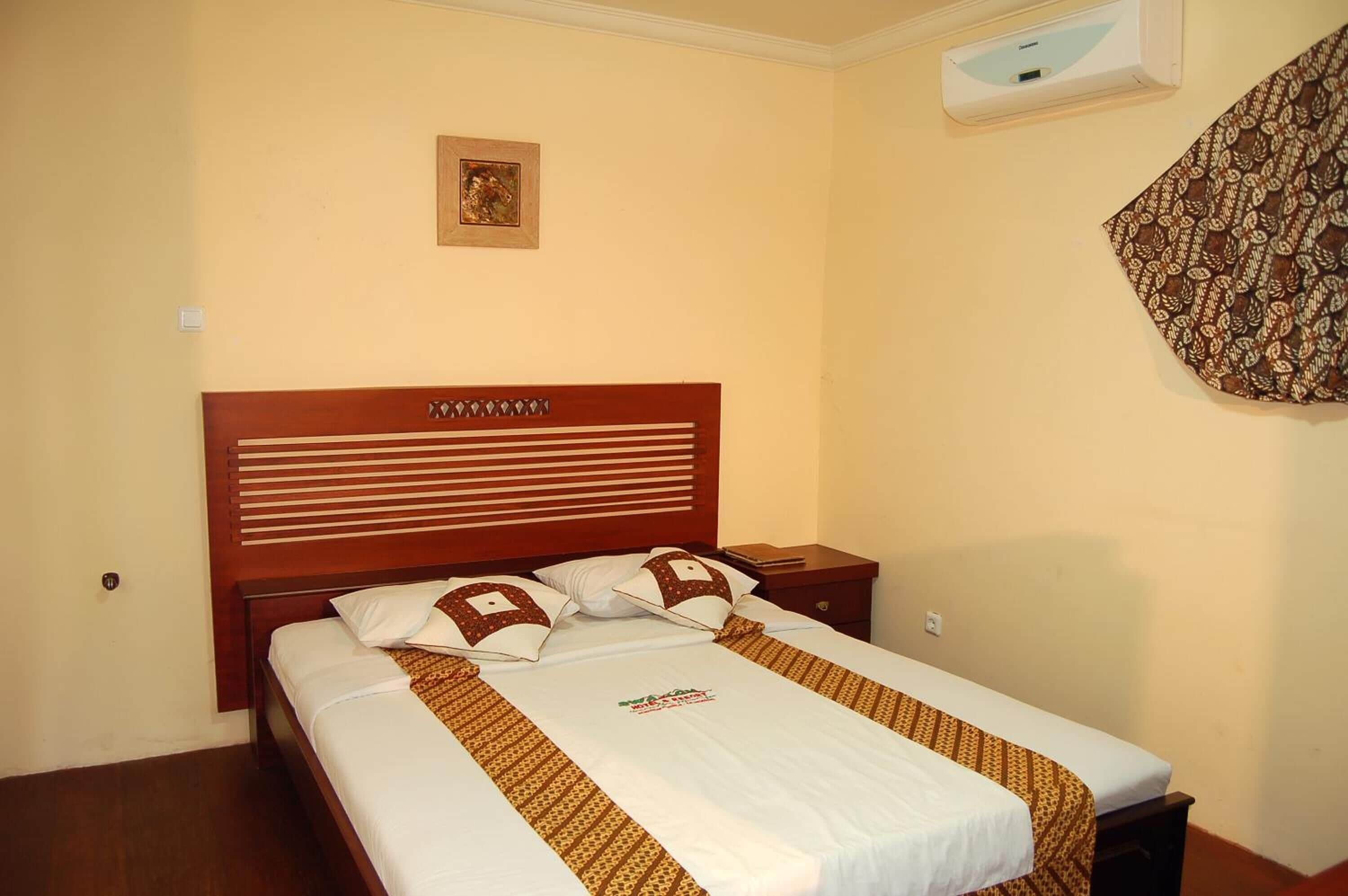 A neatly made bed with a patterned bedspread, a wooden headboard, and a small bedside table with a lamp.
