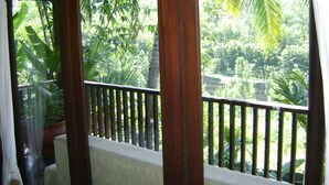 A balcony with a view of lush greenery, including palm trees and various plants. - Swaloh Hill Resort (Mulyosari)