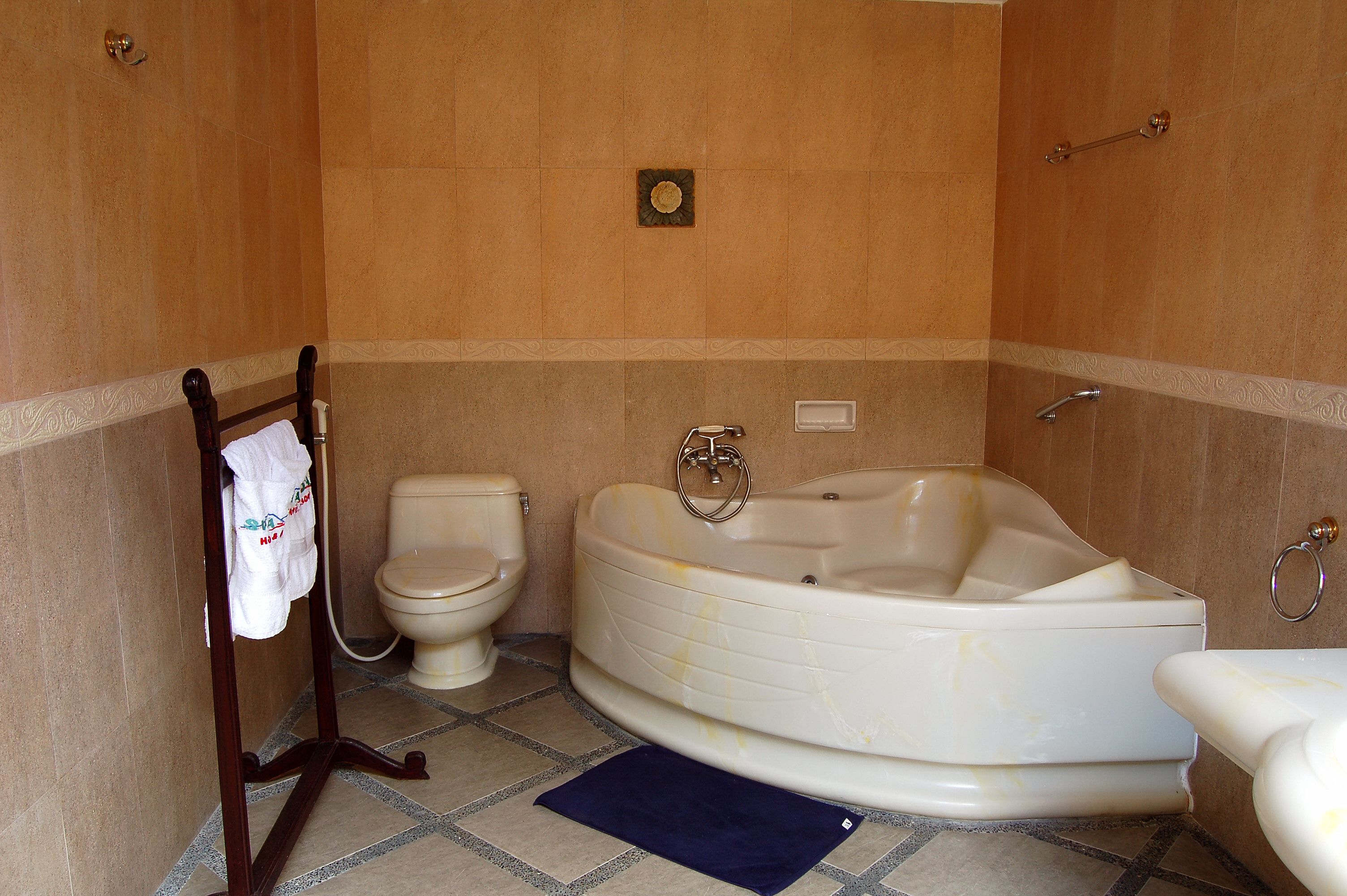 Un baño con bañera, inodoro y barra para toallas.